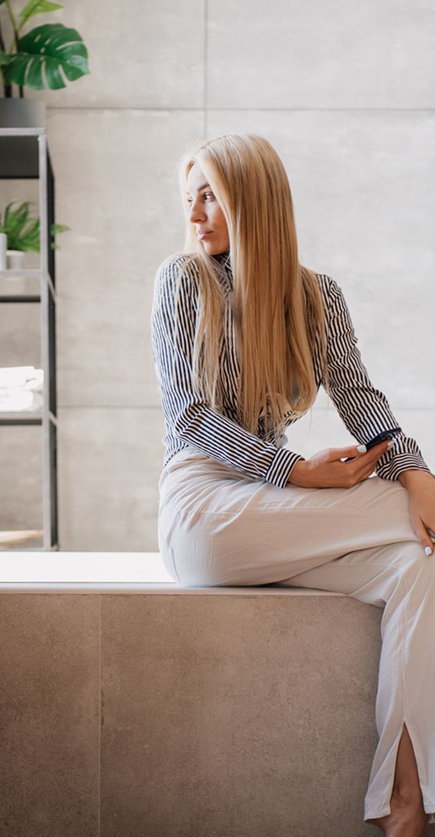 med spa patient model sitting on a ledge in modern space.