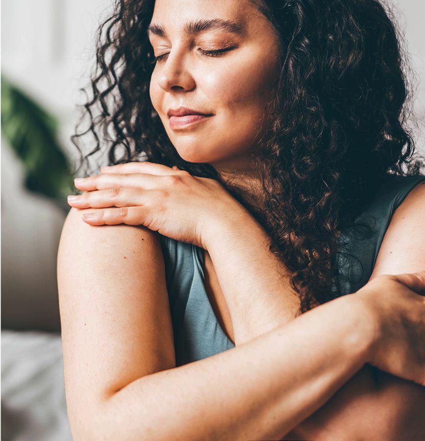 med spa patient model with curly hair embracing herself gently.