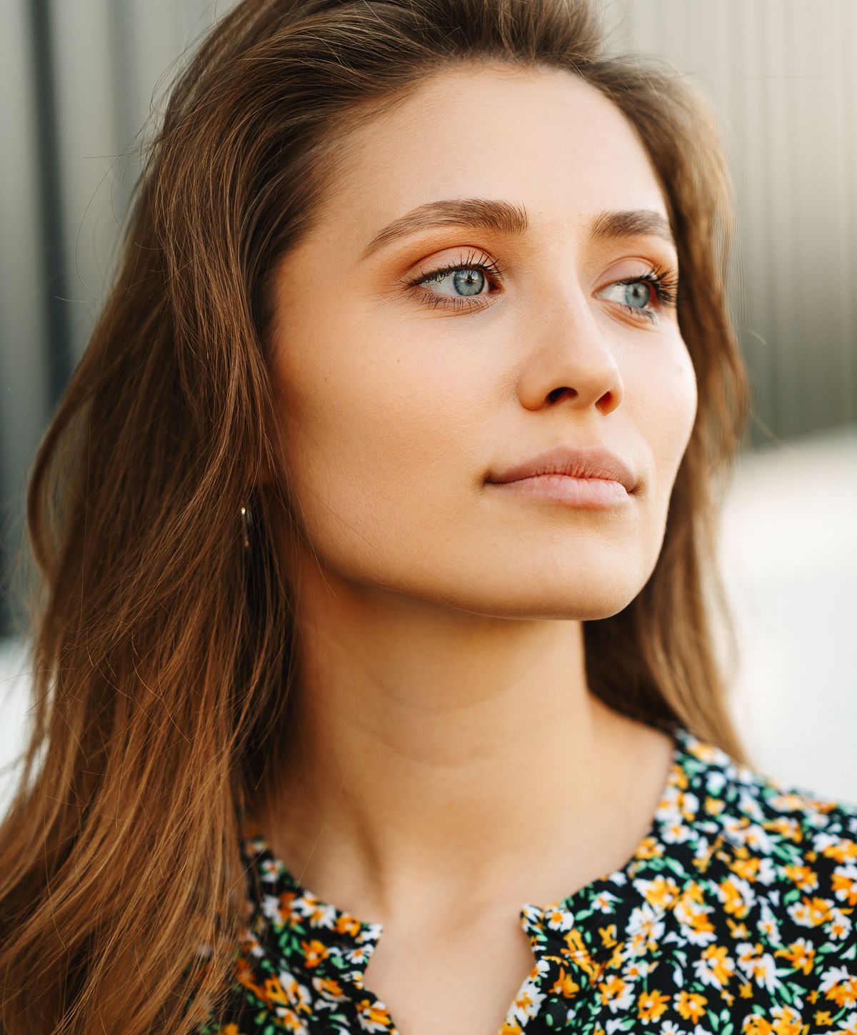 Young microneedling patient model with long hair and floral blouse.