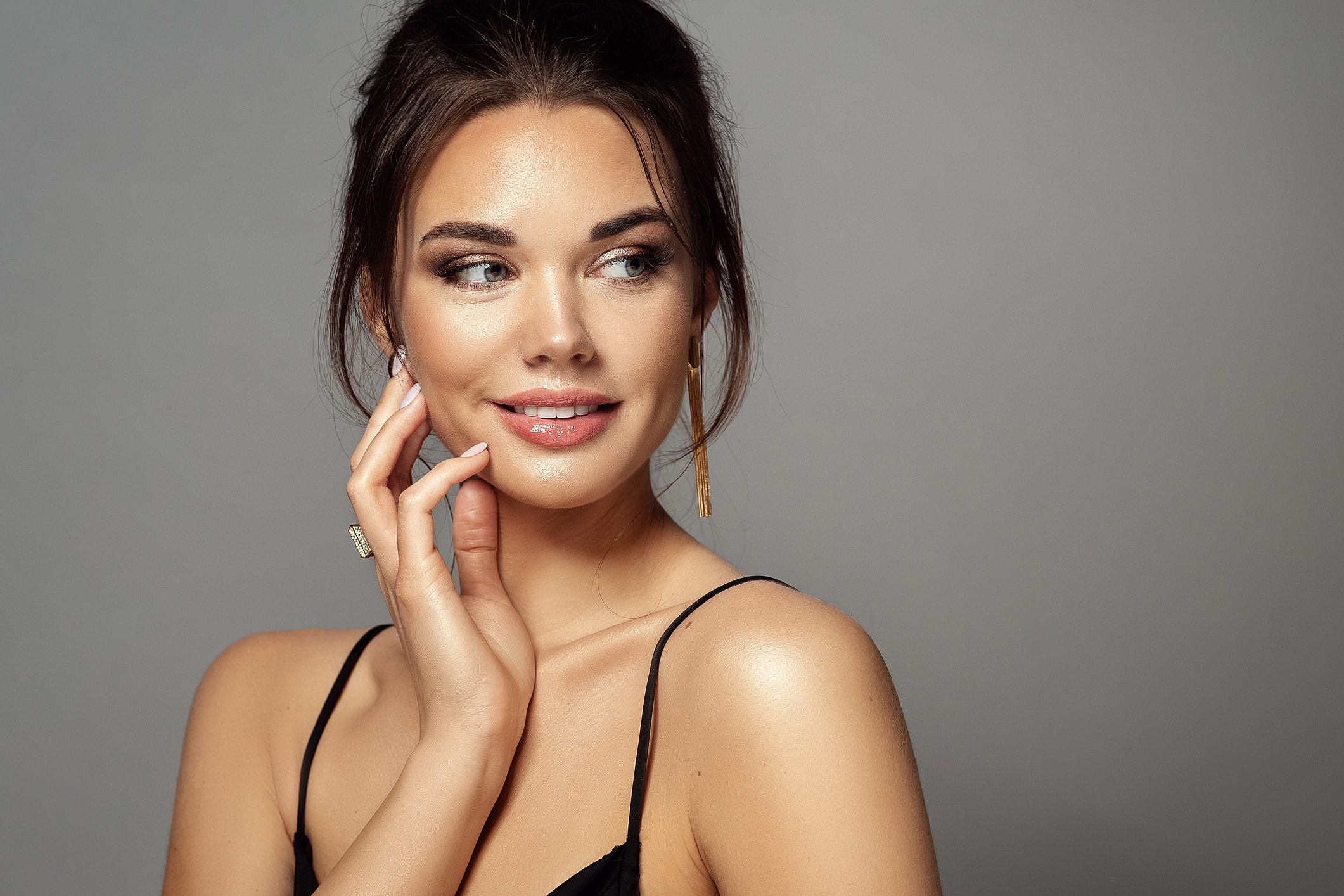 A woman with smooth, hair-free skin touches her cheek and looks off to one side.