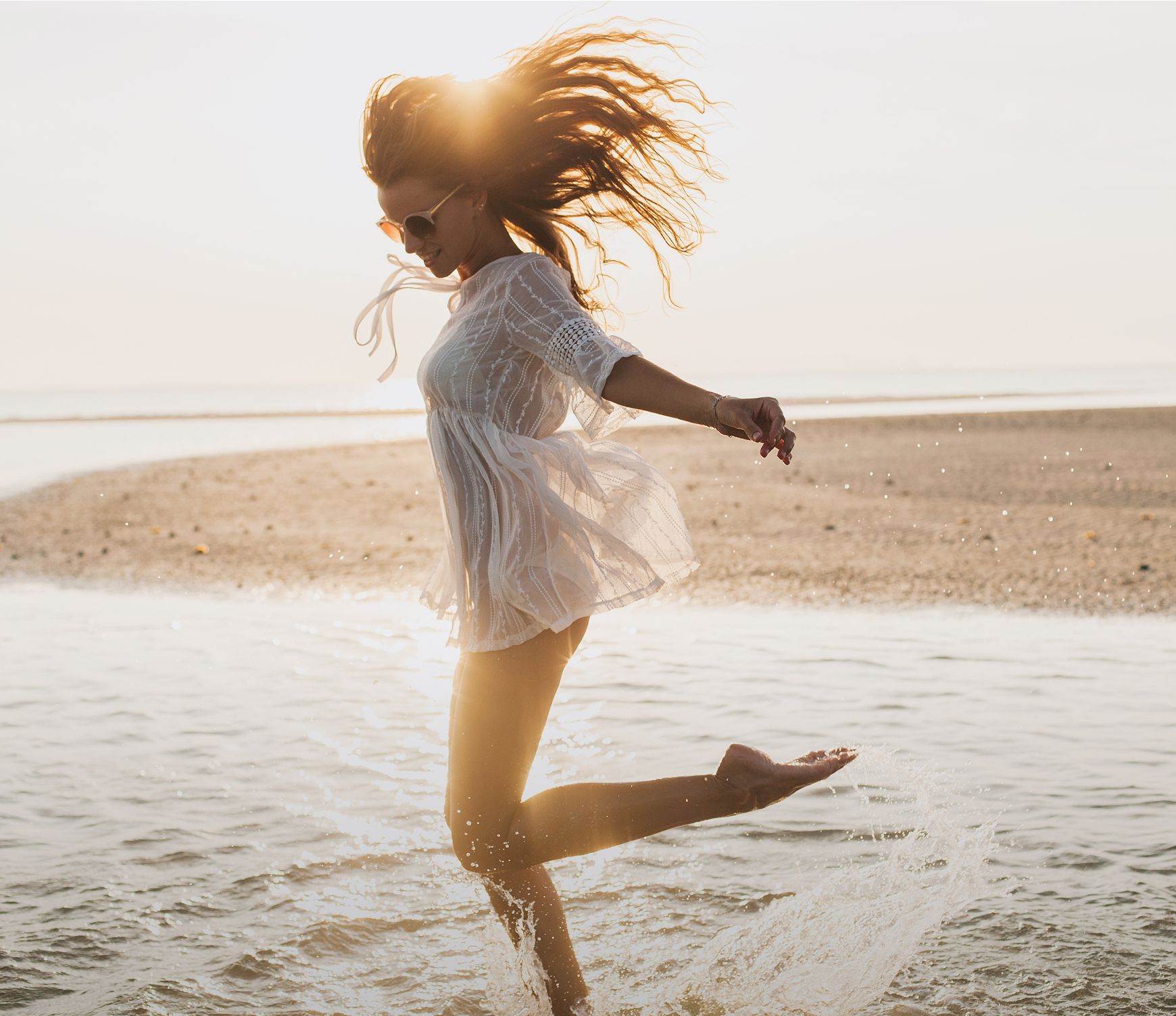 menopause treatment patient model splashing in shallow water at sunset.