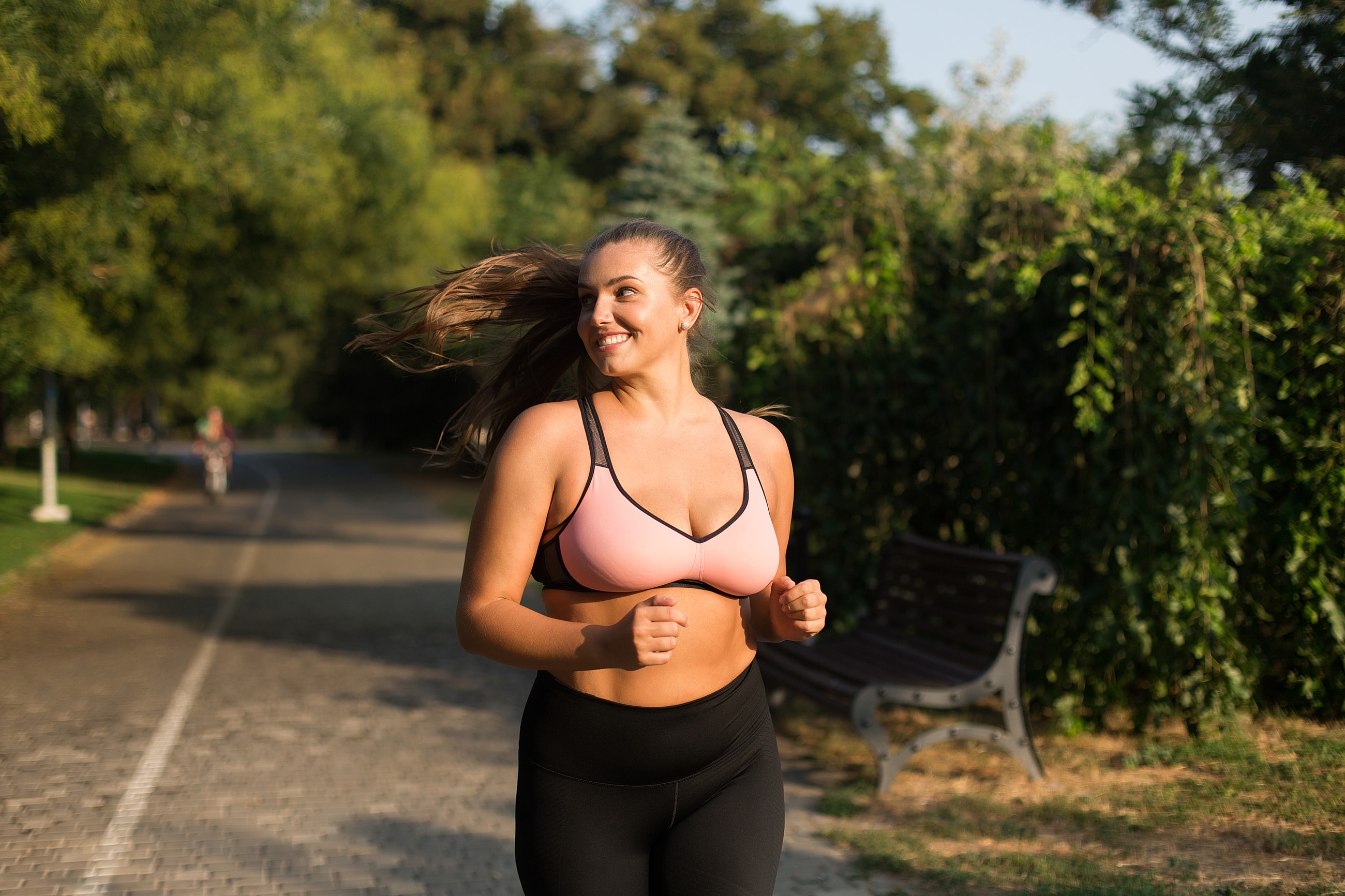 Woman jogging in park, smiling and enjoying exercise.