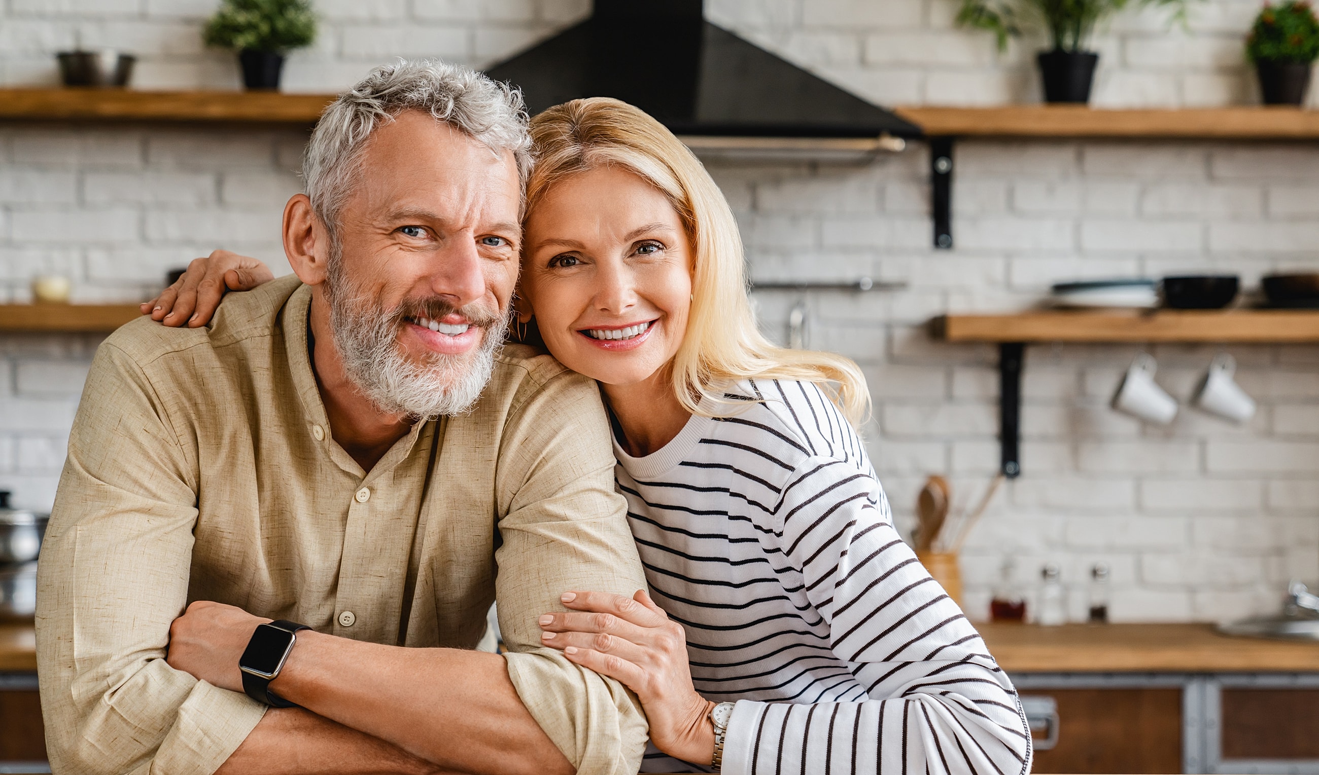 Smiling couple in a modern kitchen setting.